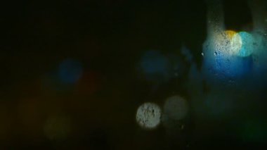 Gece aynaya 4K yağmur damlası. Fazla mesai yapan bir adamın trafik sıkışıklığının bulanık ışığıyla. Yalnızlık ve üzüntü anı. Slayt sokağında korku ve tehlike sürüyor.