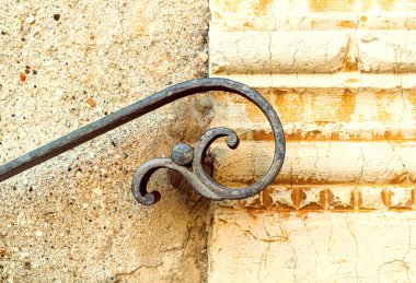 Dış duvarda eski işlenmiş demir parmaklıklar ve uçan bir insanın stilize edilmiş şekli var. Eski mermer dekorasyonun altında. Dini bir binanın girişinin dekoratif mimari detayları. Feltre, Belluno, İtalya