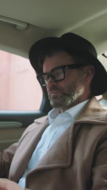 Zarif giyimli modern bir adam, bir arabanın içinde yakalandı, şehir modasının özünü gözler önüne seriyor.