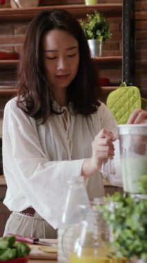 Bir kadın becerikli bir şekilde besleyici ve enerjik bir smoothie 'yi harmanlarken aynı zamanda canlı bir mutfak ortamı sergiliyor.