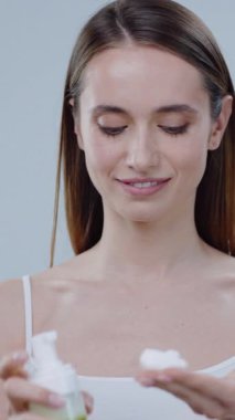 Bir kadın nazikçe nemlendirici sürerek cildini sağlıklı ve parlak ciltler için ön plana çıkarır.