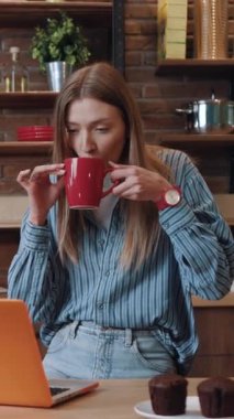 Genç bir kadın, yaratıcılık için tasarlanmış şık ve rahat bir çalışma alanında dizüstü bilgisayarına derinden konsantre oluyor.