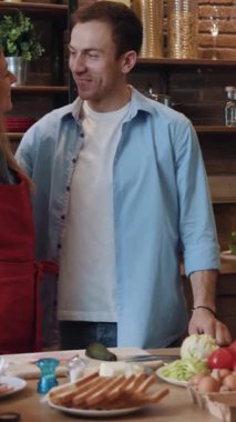 Neşeli bir çift birlikte lezzetli bir yemek pişiriyor, mutfaklarında sevgi ve bağ kuruyorlar.