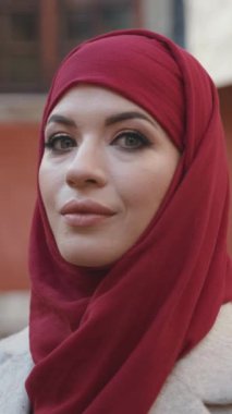 Zarif bir kadın benzersiz cazibesini kırmızı bir eşarpta sergiliyor. Canlı bir şehir zeminiyle güzel zıt düşüyor.