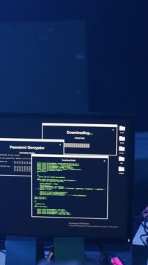 Loş bir odada, bir kişi can alıcı bir indirme yapan bir monitörü endişeyle izlerken gerginlik yükselir. Yakın çekimler gergin ellerini ve kelepçeli bileklerini gösteriyor.