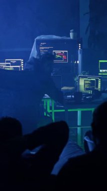 Loş bir odada, çeşitli bir grup, kırmızı kapüşonlu bir adamla gizemli bir mesajın merkezindeki bir projede işbirliği yapıyor.