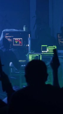 Loş bir odada, bir siluet teknolojiyle uğraşırken heyecan içinde kollarını kaldırır. Bilgisayarda odaklanmış bir kişi Ubuntu gösterir