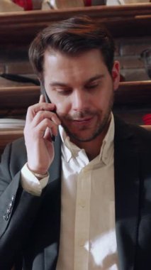 Profesyonel bir adam, şık ve modern bir çalışma alanında bulunduğu sürece aktif olarak bir telefon görüşmesi yapmaktadır.