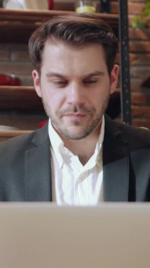 Odaklanmış bir profesyonel, görevlerini yerine getirirken şık bir kafe atmosferinin tadını çıkarırken uzak çalışmalarını somutlaştırır.