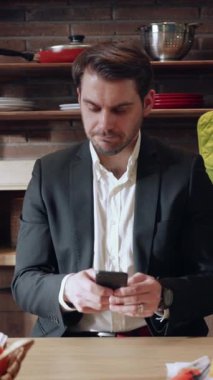 Odaklanmış, kendini işine adamış bir işadamı şık ve çağdaş bir ortamda bulunurken akıllı telefonunu dikkatle kontrol ediyor.