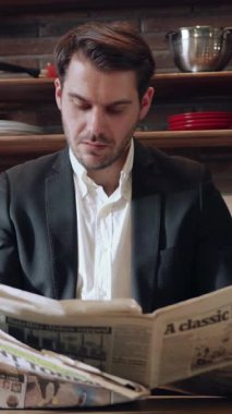 Profesyonel olarak giyinmiş bir adam evinde rahatça dinlenirken gazete okumakla ilgilenir.
