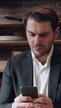 Zarif bir takım elbise giymiş keskin bir işadamı modern ofis ortamında akıllı telefonuna odaklanır.