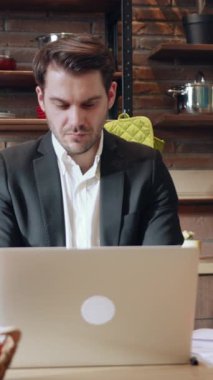 Şık bir takım elbise giymiş odaklanmış bir adam modern ve çağdaş bir ofis ortamında özenle dizüstü bilgisayarıyla çalışır.