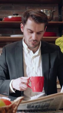 Genç bir profesyonel şık ve modern bir kafe ortamında gazete okurken bir fincan kahvenin tadını çıkarıyor.