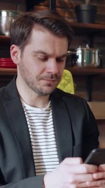 Modern bir kafede akıllı telefonuyla meşgul olan şık bir adam.