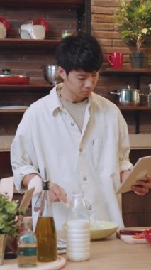 Genç bir adam, taze malzeme ve aletlerle dolu modern bir mutfakta ustalıkla lezzetli bir yemek pişirir.