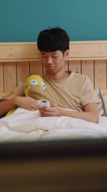 Rahat döşenmiş ve rahat bir yatak odasında genç bir adam sevgili pelüş oyuncağıyla sevgi dolu anların tadını çıkarıyor.