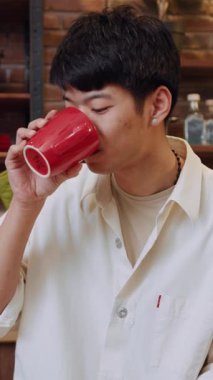 Sıcak ve davetkar bir yerde, genç bir adam laptopuyla uğraşırken rahatça kahvesini yudumluyor.