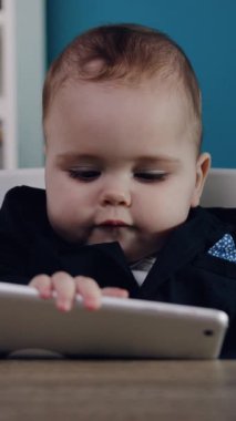 Meraklı bir bebek, teknolojiye ve dijital keşiflere erken maruz kalan renkli bir tabletle ilgilenir.