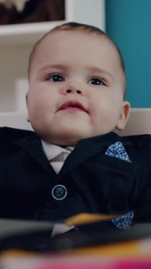 Zarif bir takım elbise giymiş sevimli küçük bir bebek büyüleyici ve modaya uygun bir anı yakalıyor.