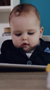 Zarif bir takım elbise giymiş küçük bir çocuk modern bir tabletle uğraşıyor, teknolojiyle masumiyeti birleştiriyor.