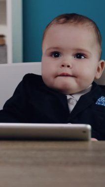 Şık takım elbiseli şirin bir bebek iş ve oyunculuğun özünü harmanlamak için ustalıkla tablet kullanır.