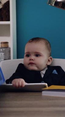 Şık takım elbiseli genç bir çocuk, dizüstü bilgisayarı olan düzgün bir masada oturuyor, profesyonelliği ve hırsı özetliyor.