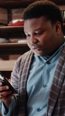 Genç bir adam, sıcak ve davetkar bir atmosferle çevrili akıllı telefonunun küçük ekranına tamamen dalmış durumda.