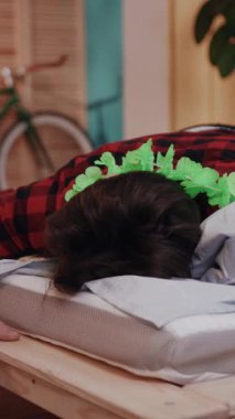 Bir insan, rahat bir ortamda canlı bir çiçek aksesuarıyla süslenmiş bir yatakta huzur içinde dinleniyor.