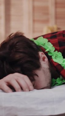 Bir insan, canlı ve renkli bir tropikal aksesuar giyerken yumuşak beyaz bir yüzeyde yüzükoyun dinlenir.