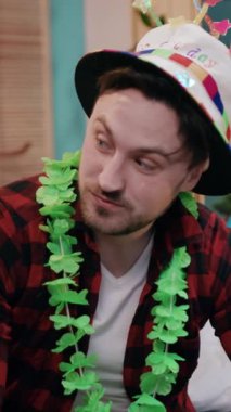 Neşeli bir adam, renkli bir parti şapkası ve canlı bir çelenk takarak, etrafındaki hayat dolu atmosferden zevk alır.