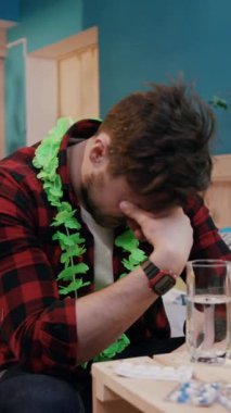 Renkli bir ekose gömlek giymiş bir adam, arkasına yaslanır ve canlı bir tropikal lei giyerken derin derin düşünür,