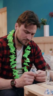 Parlak yeşil Hawaii kolyesi takan bir adam evinde yaratıcı bir aktiviteyle meşgul.