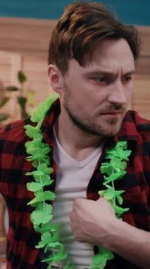 Canlı yeşil bir lei giyen bir adam, bir toplantı sırasında sıradan bir kapalı ortam içinde endişeli görünür.