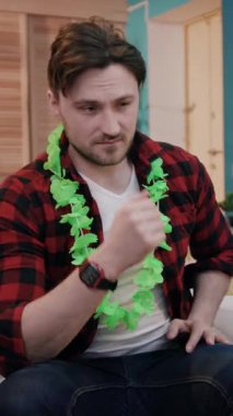 Canlı yeşil bir lei giymiş bir adam, rahat bir iç mekanda dalgın dalgın dalgın dalgın dalgın dalgın dalgın dalgın dalgın dalgın dalgın dalgın dalgın dalgın dalgın dalgın dalgın dalgın dalgın dalgın dalgın dalgın oturuyor.