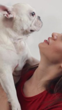 Çok sevdiği köpeğiyle neşeyle özel bir anı paylaşan bir kadının hoş ve iç açıcı portresi.