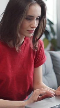 Odaklanmış bir kadın özenle dizüstü bilgisayarında yazıyor. Evde sıcak ve davetkar bir iş ortamı yaratıyor.