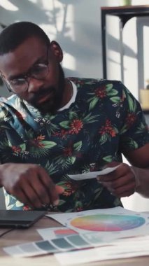 Kendini adamış ve odaklanmış bir birey şık bir çalışma ortamında çeşitli renk paletlerini titizlikle analiz ediyor.