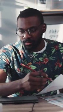 Genç bir profesyonel, yaratıcılık ve verimliliği vurgulayarak modern bir çalışma alanında çizelgeleri inceliyor..