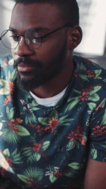 Bu adam renkli bir gömlek giyiyor ve gözlük takıyor. Karizma, zeka ve tarz yayıyor.