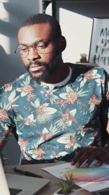 Şık giyimli bir adam, canlı bir çalışma alanında dizüstü bilgisayarı üzerinde çalışırken yaratıcı işlerle çok ilgilidir.