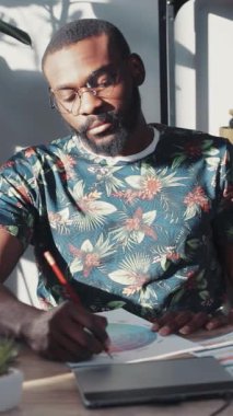 Canlı çiçekli gömlekli bir adam, yaratıcılığını ve üretkenliğini gösteren yazıya dalmıştır.