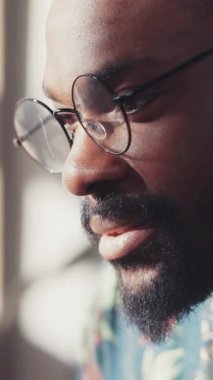 Gözlüklü düşünceli bir adam, yumuşak, rahatlatıcı doğal ışıkla aydınlatılmış sakin bir ifade sunar.