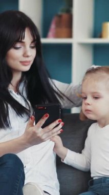 Bir anne ve genç kızı, modern bir yaşam alanında akıllı telefondan keyif alarak birlikte kaliteli zaman geçiriyorlar..