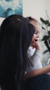 Bir anne ve küçük çocuğu bir tabletle neşeyle etkileşime geçerek hassas bir bağ kurma anı sergiliyorlar.