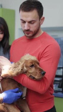 Sevgi dolu bir adam sevimli köpeğini sıcak ve davetkar bir ortamda birlikte dururken nazikçe tutar.