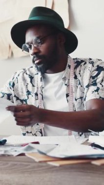 Odaklanmış bir tasarımcı, canlı bir çalışma alanında araçlar ve malzemeler kullanarak yenilikçi moda kavramları çizer