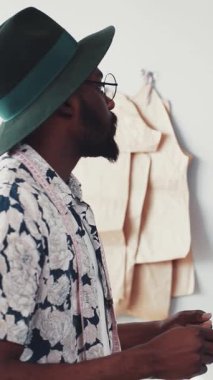 Şık ve şık bir adam çarpıcı yeşil bir şapka giyer. Canlı bir çiçekli gömlekle eşleşir. Modern bir estetiği somutlaştırır.