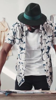 Canlı bir çiçek gömleği ve şapkayla süslenmiş şık bir adam. Yaratıcı çalışmalarına dalmış.