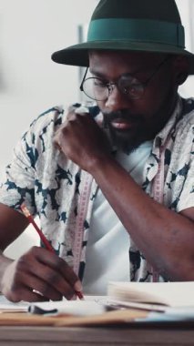 Şık şapkalı şık bir adam, eşsiz yaratıcı bir çalışma alanında yazarken derin düşüncelere dalıyor.